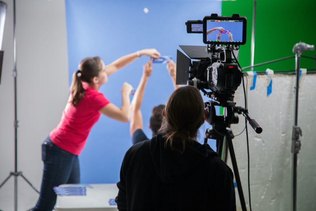 Benefits of video marketing: Camera operator in foreground adjusts a shot as other video crew members hold a prop.