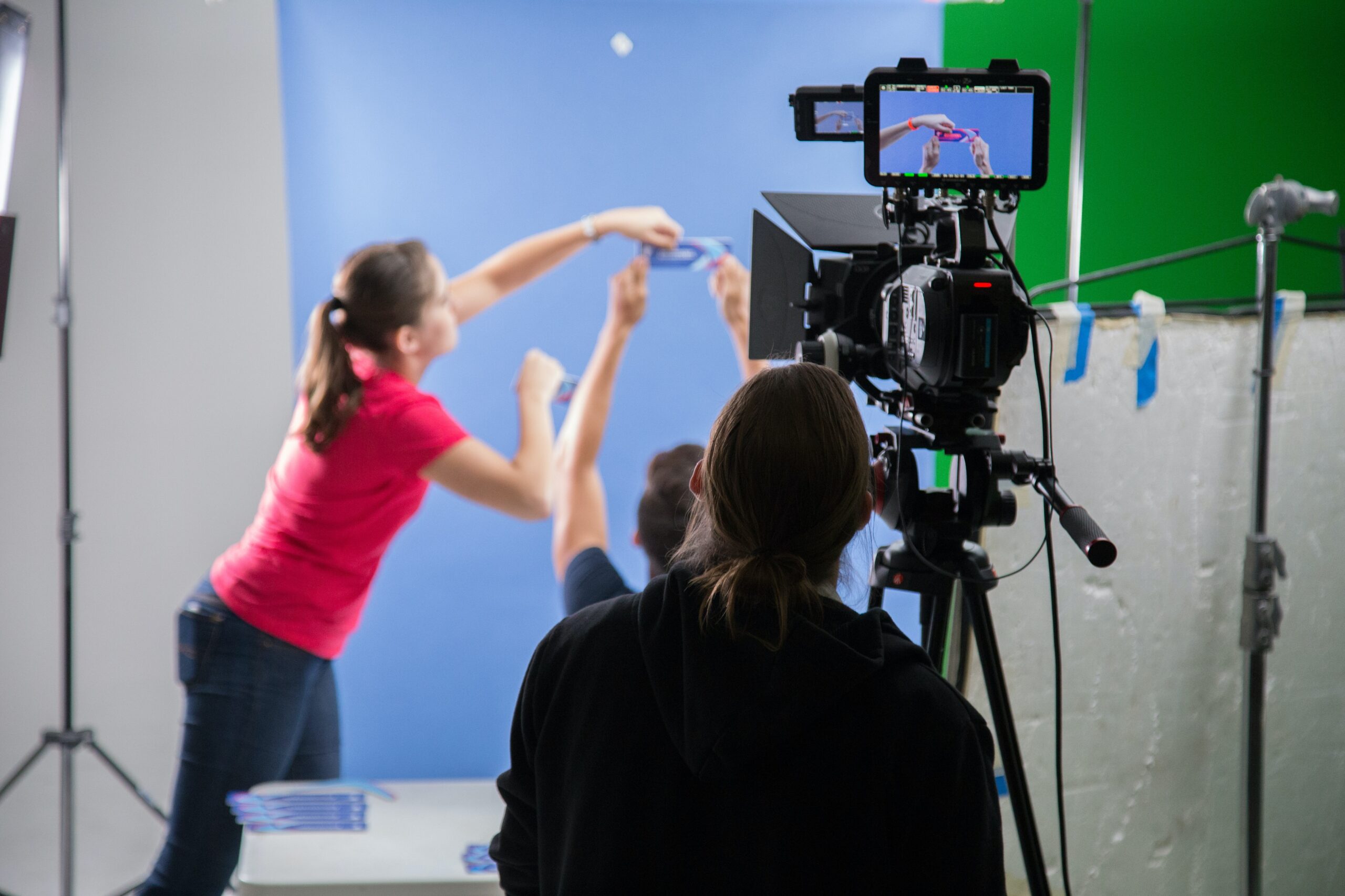 Benefits of video marketing: Camera operator in foreground adjusts a shot as other video crew members hold a prop.