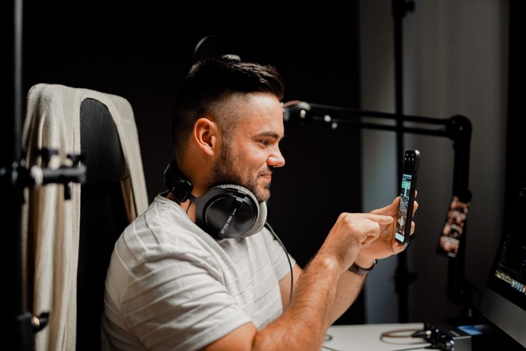 A multimedia work station where a man engages in video marketing production with smartphone, microphone, etc.