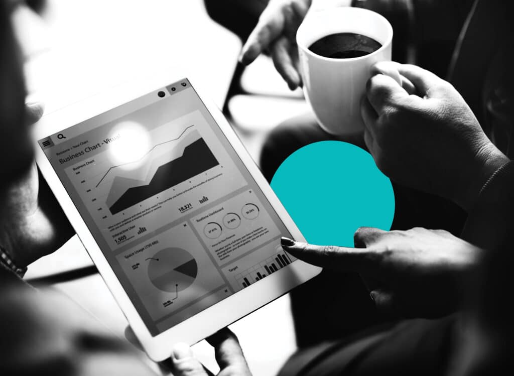 A closeup of an ipad displaying sales and marketing software analytics as several colleagues look on.