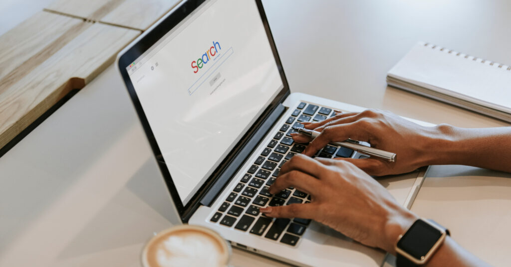 Close up of brown hands using a laptop to enter a SEO FAQ into a search engine