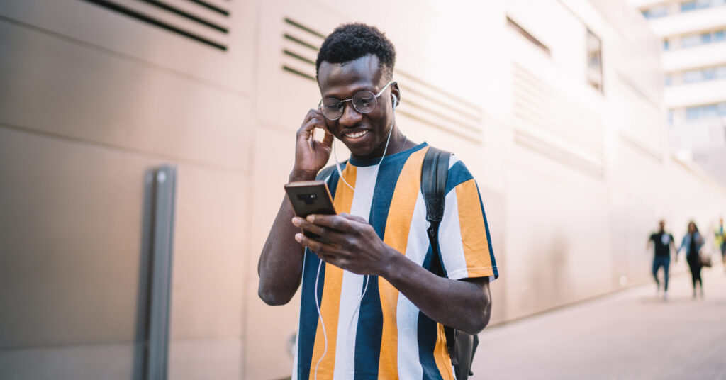 Happy customer, a black man, checks his email on his smartphone.