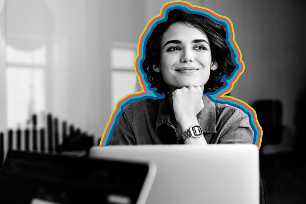Smiling woman in black and white seated in front of her laptop.