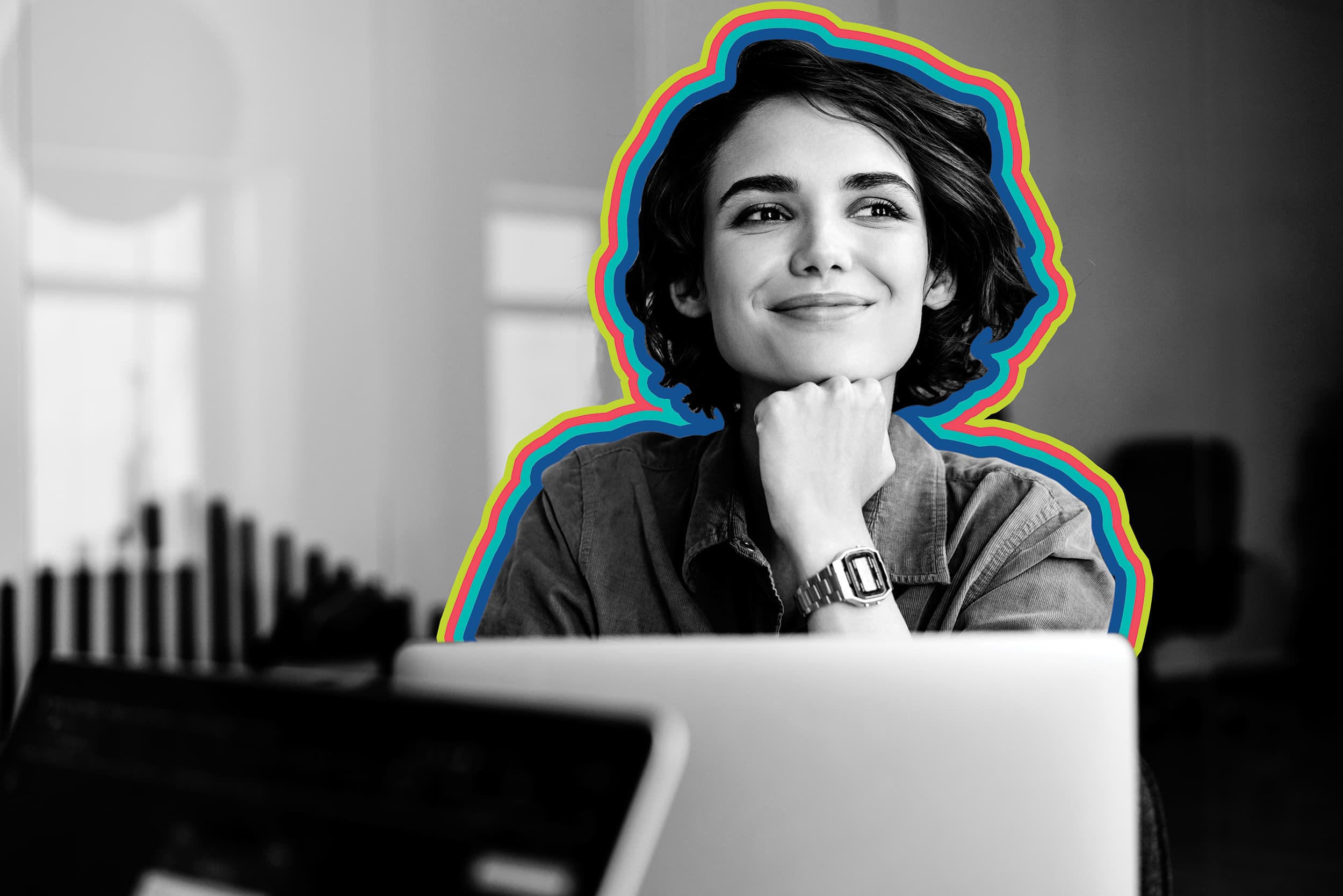 Smiling woman in black and white seated in front of her laptop.