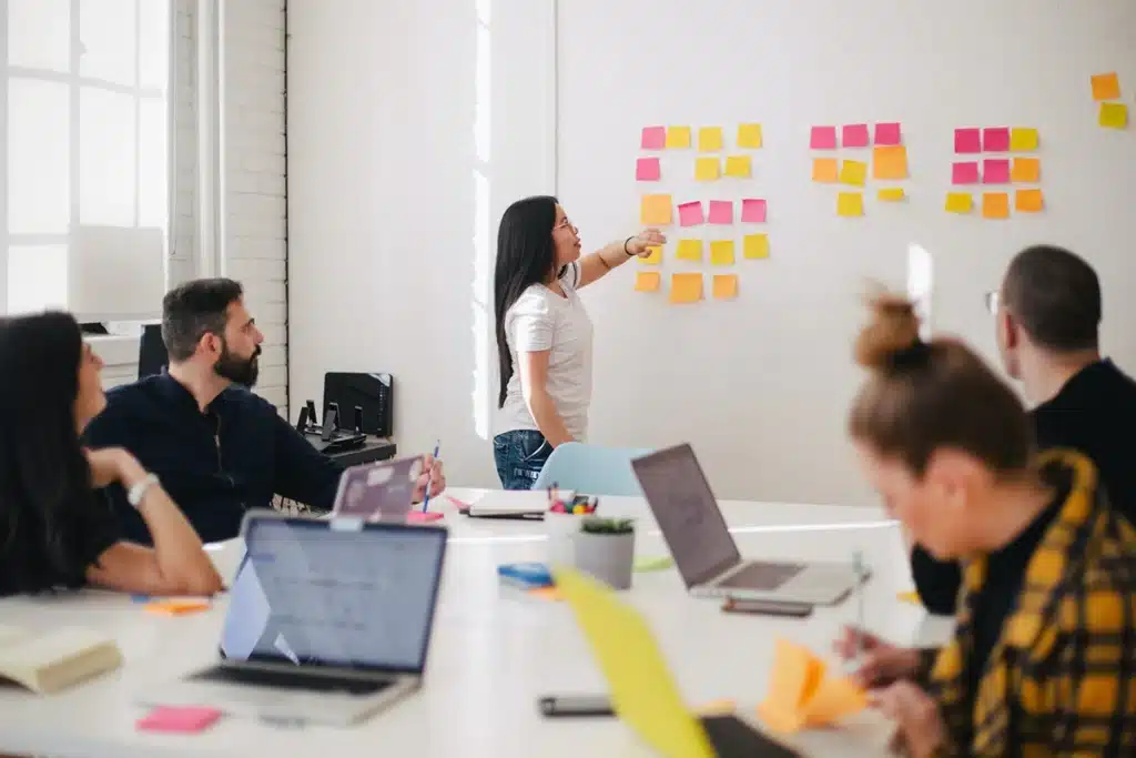 Coworkers in a white conference room with post-its on the wall planing a webinar.